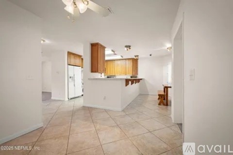 A kitchen with white walls and wooden cabinets is available for rent.