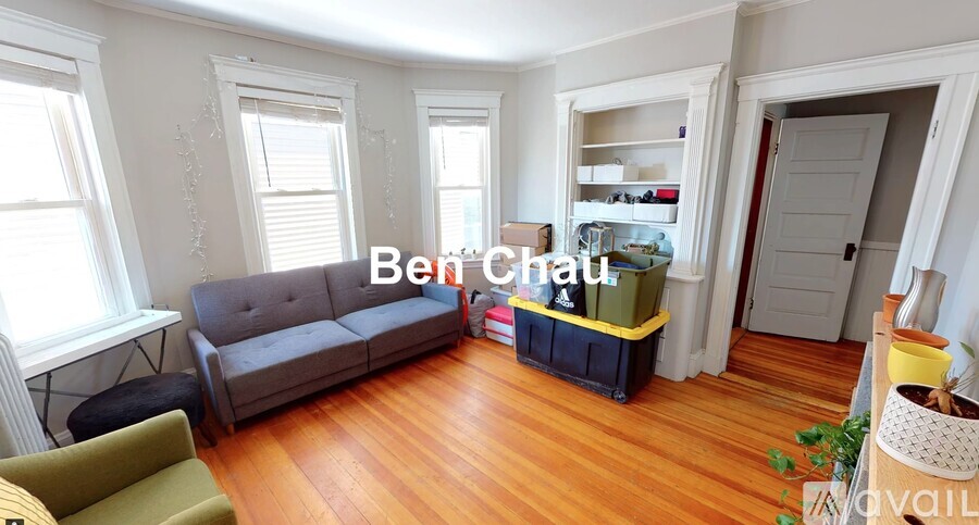 A living room with a grey couch and a yellow container on the floor.