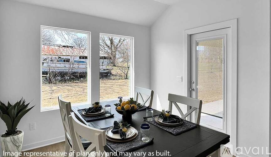 A dining room with a table set for two and a view of a parking lot outside.