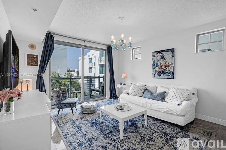 A living room with a white couch and a blue patterned rug.