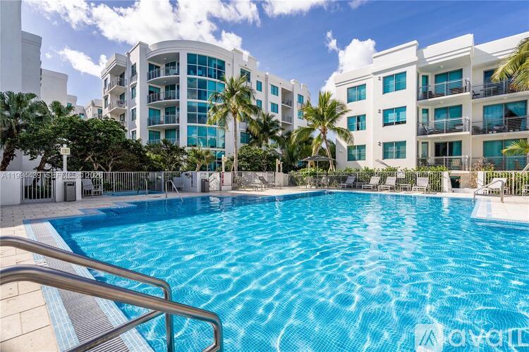 A swimming pool in front of a white building with palm trees.