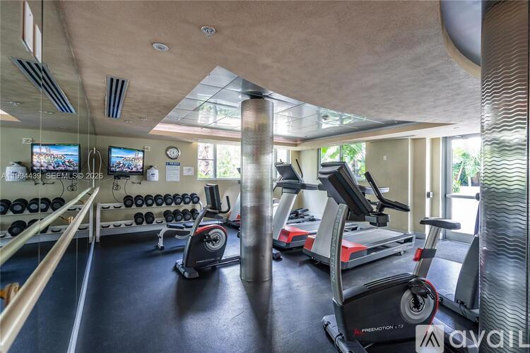 A gym with treadmills, elliptical machines, and dumbbells.