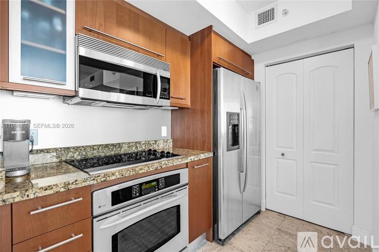A kitchen with a stainless steel refrigerator and oven, and wooden cabinets.