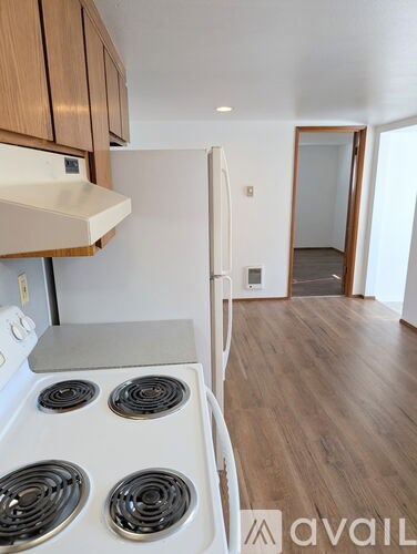 A kitchen with a white stove top oven and wooden cabinets.