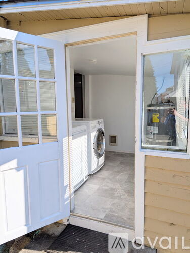A white door is open to a room with a washing machine.