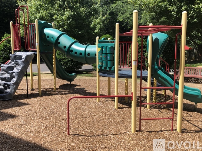 A playground with a green slide and a red metal structure.