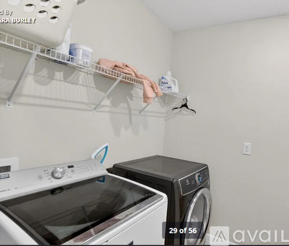 A person is hanging a white shirt on a hanger in a laundry room.