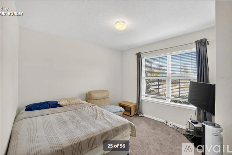 A bedroom with a bed, a chair, and a window with blinds.