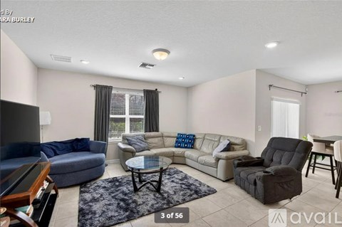 A living room with a grey sofa, a black chair and a glass table.