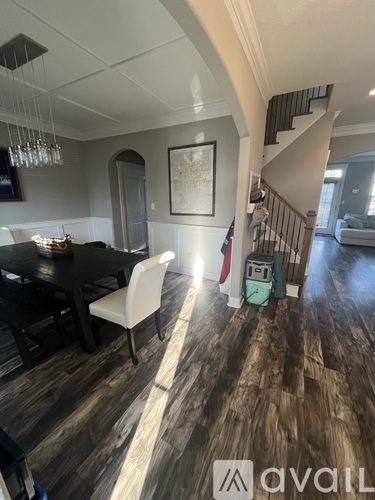 A dining room with a wooden floor and a staircase.
