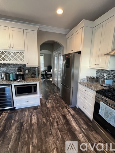 A kitchen with white cabinets and a wooden floor.