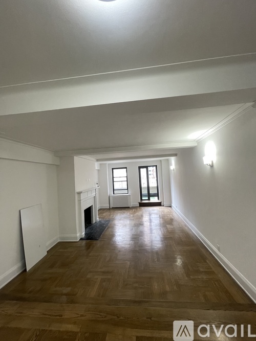 A room with wooden floors and a fireplace with a door leading to another room.
