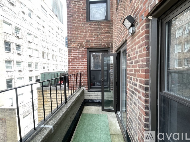 A balcony with a green carpet and a brick wall.