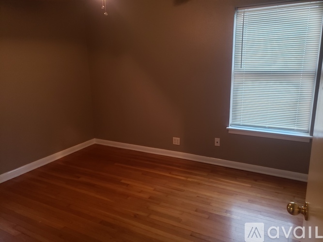 A room with wooden flooring and a window with blinds.