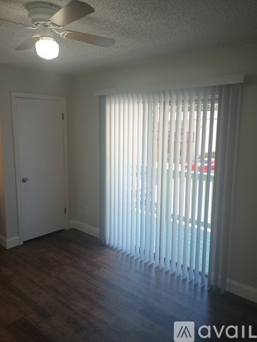 A room with a ceiling fan and a window with blinds.