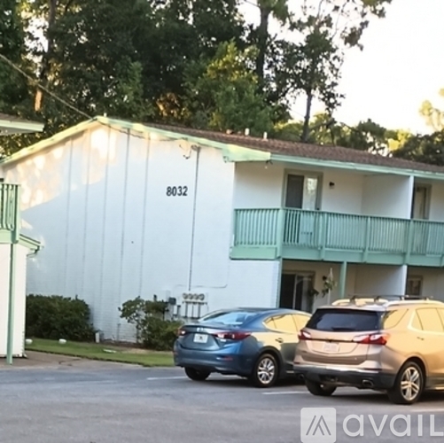 Two cars parked in front of a white building with the number 8032 on it.