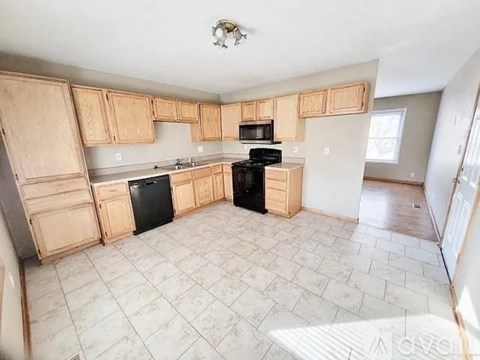 A kitchen with black appliances and wooden cabinets.