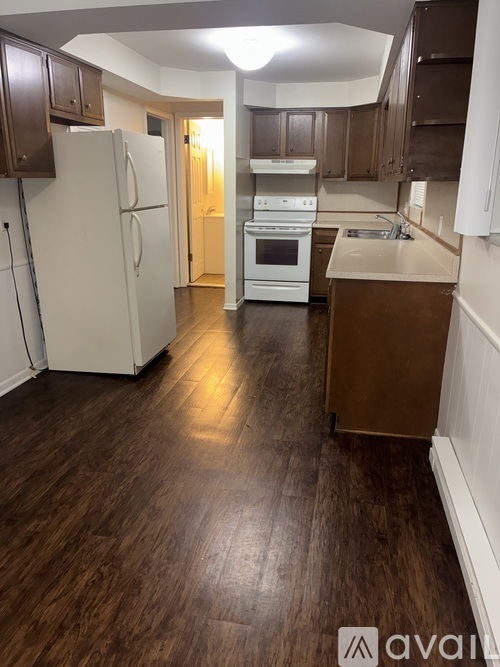 A kitchen with a white refrigerator and wooden floors.