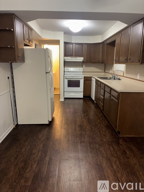 A kitchen with a white refrigerator and wooden cabinets.