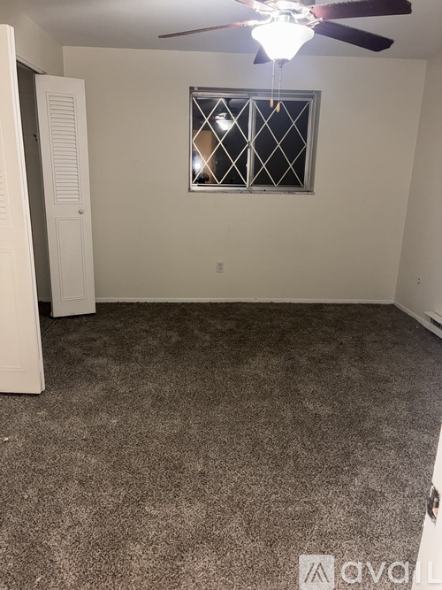 A room with a ceiling fan and a window with bars.