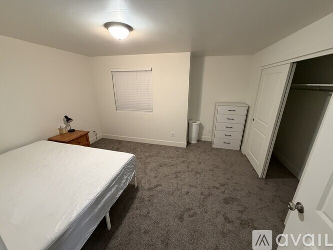 A bedroom with a bed, nightstand, and dresser.
