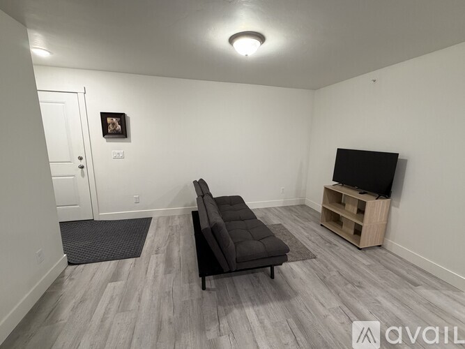 A living room with a black couch and a wooden entertainment center.