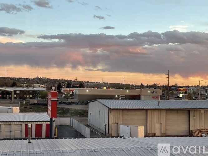 A view of a parking lot with a building and a red sign in the foreground.