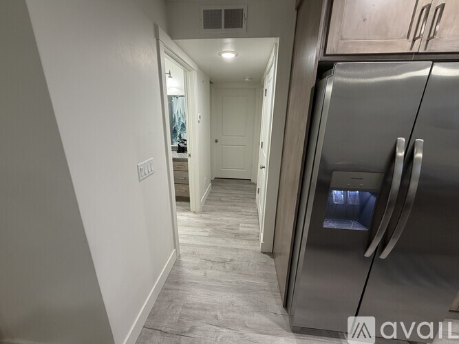 A kitchen with a stainless steel refrigerator and wooden cabinets.