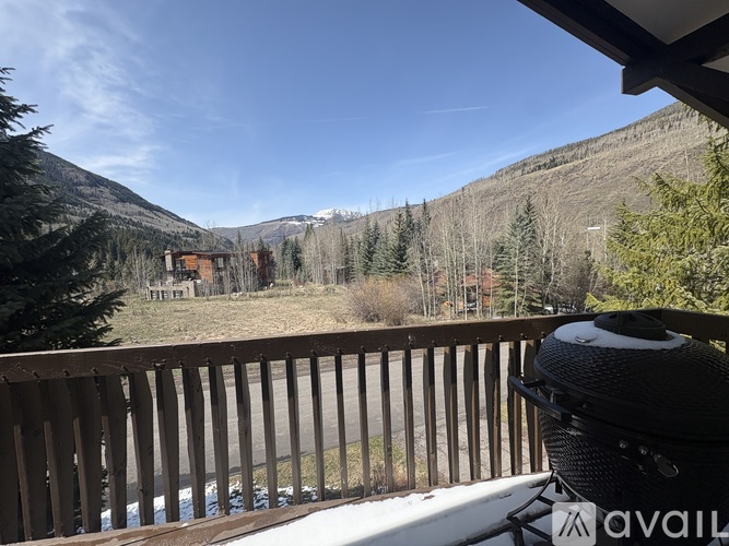 A BBQ grill is on a deck overlooking a snowy mountain.