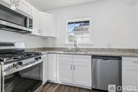 A kitchen with white cabinets and a granite countertop.