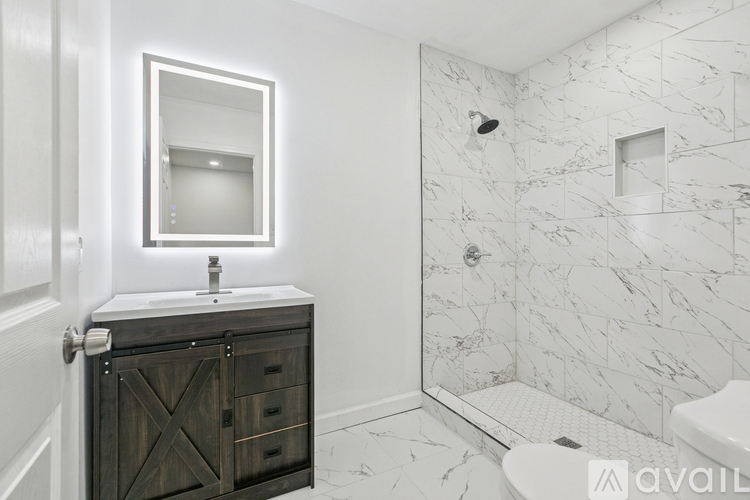 A bathroom with a marble tile shower and a wooden vanity.