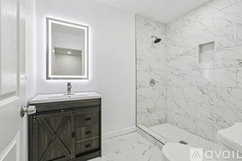A bathroom with a marble tile shower and a wooden vanity.