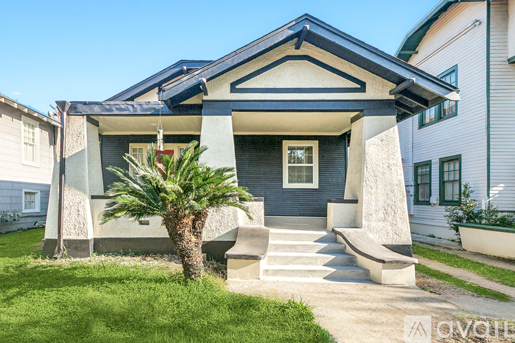 A house with a blue roof and a palm tree in front.