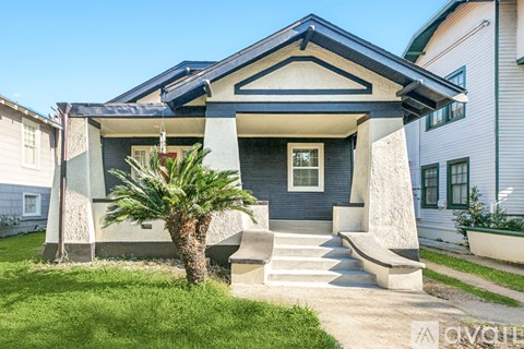 A house with a blue roof and a palm tree in front.