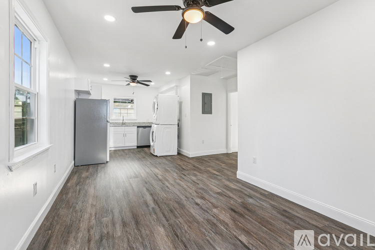 A spacious room with a ceiling fan and a refrigerator.