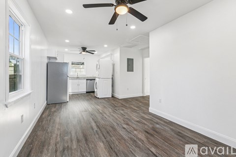 A spacious room with a ceiling fan and a refrigerator.