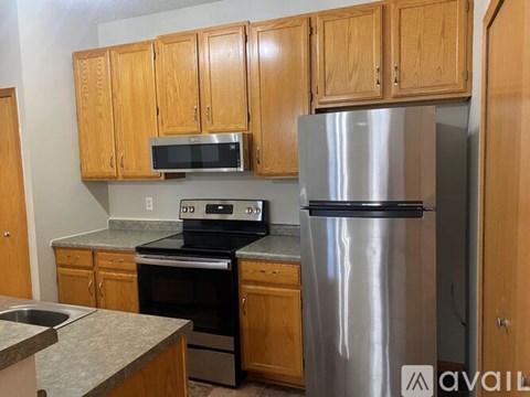 A kitchen with wooden cabinets and a stainless steel refrigerator.