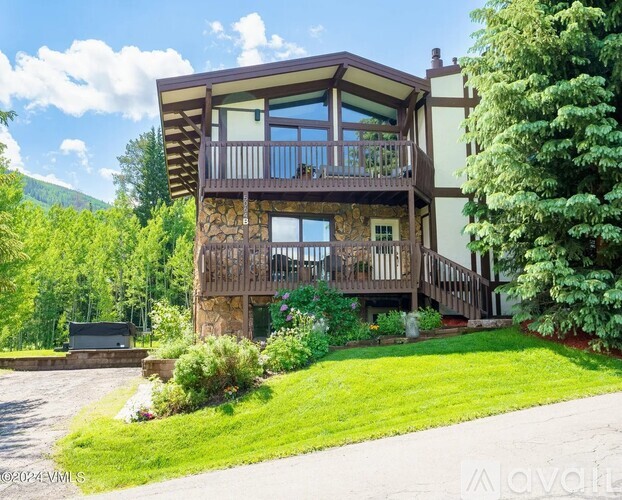 A wooden house with a balcony and a driveway in front.