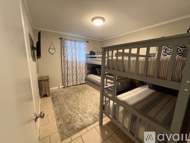 A bedroom with a bunk bed and a window with curtains.