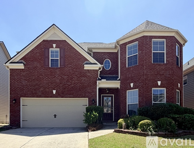 A red brick house with a garage door and a driveway.