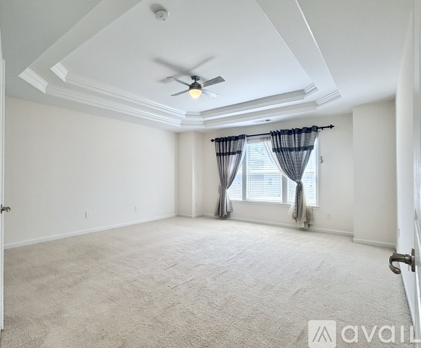 A spacious room with a ceiling fan and carpeted floor.