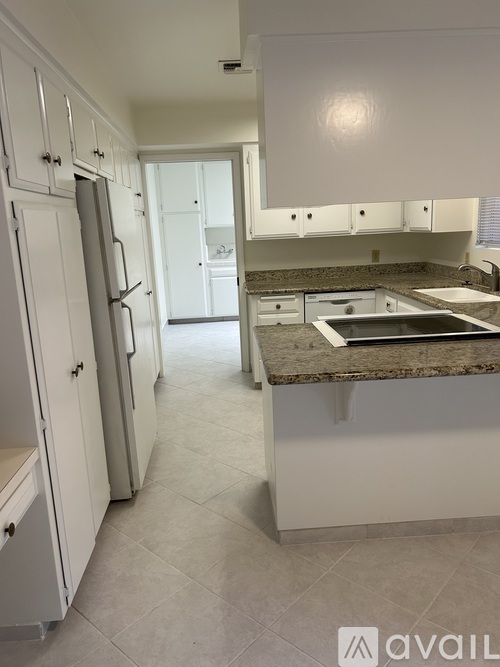 A kitchen with white cabinets and a granite countertop.