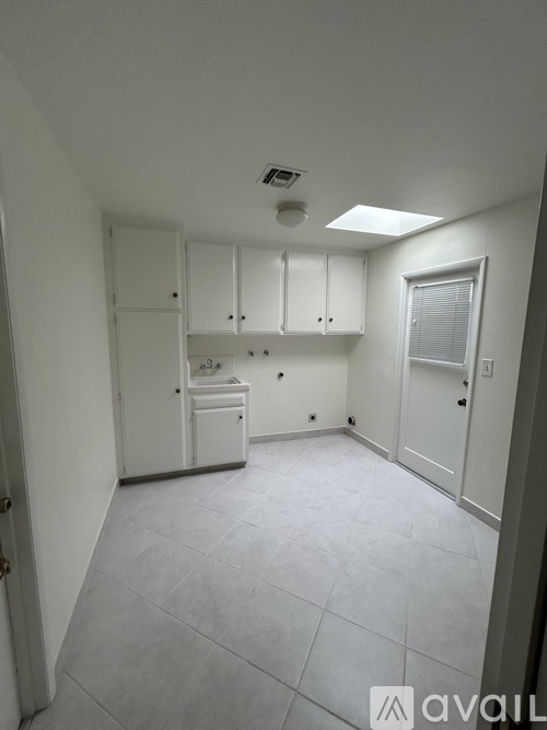 A kitchen area with white cabinets and a window.