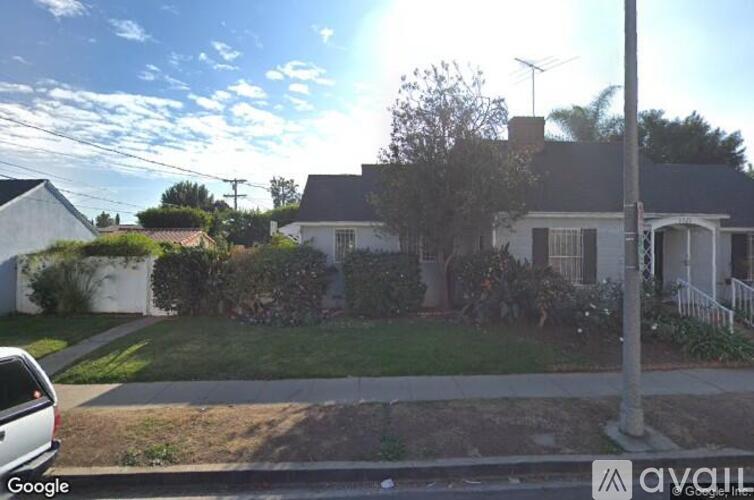 A house with a white fence and a tree in front.
