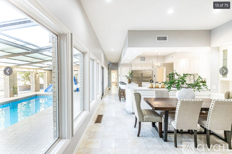A modern dining room with a pool outside the window.
