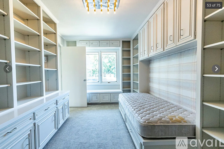 A bedroom with a bed, shelves, and a window.