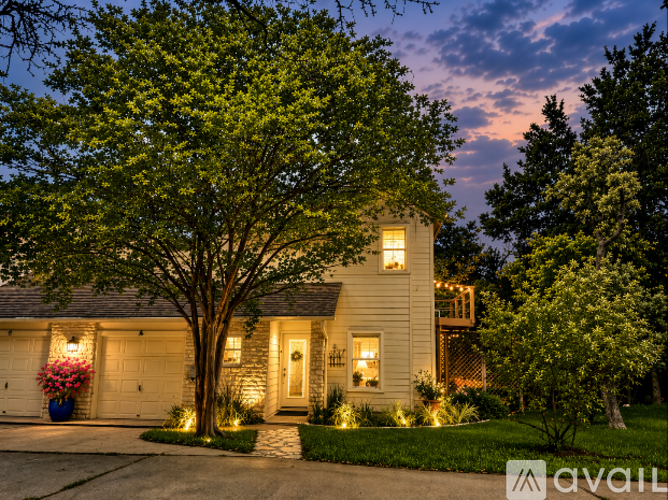 A house with a tree in front of it is lit up at dusk.