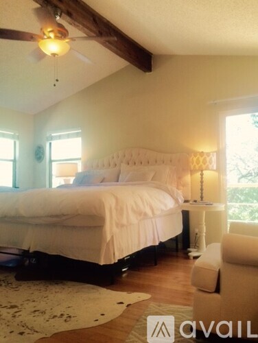 A bedroom with a large bed and a ceiling fan.