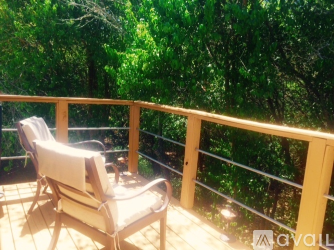 A chair is on a balcony with trees in the background.