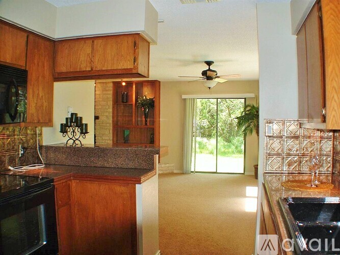 A kitchen with wooden cabinets and a black microwave.